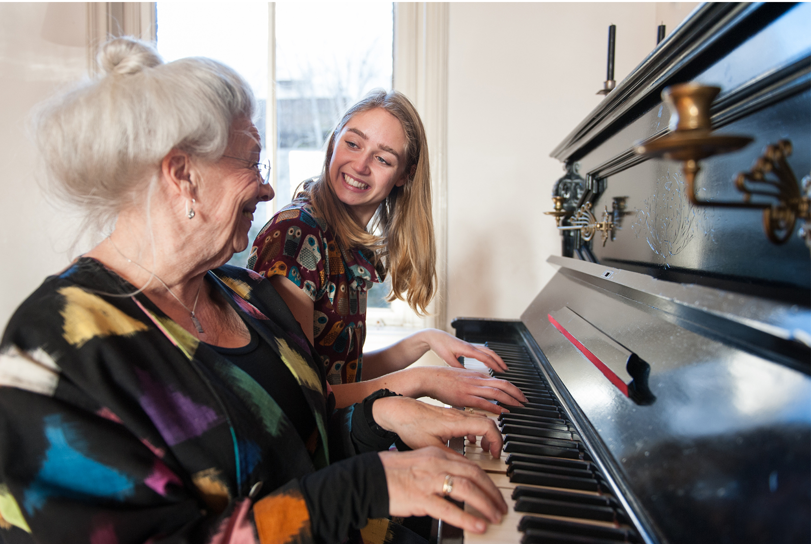 Teenage girl and older lady playing piano together