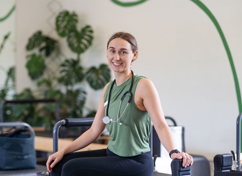 Esme Soan seated on a reformer pilates bench.