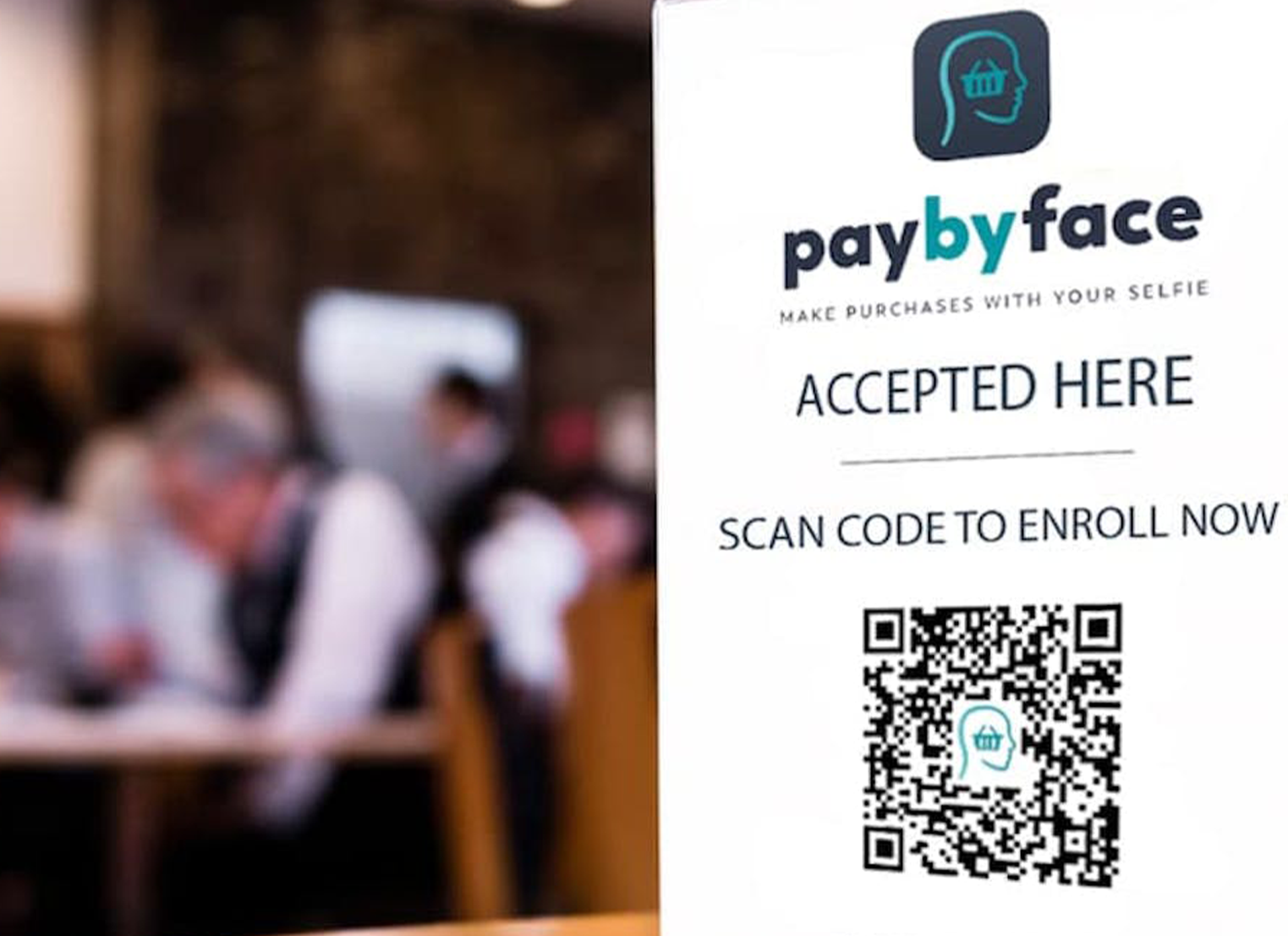 A 'paybyface' advertisement showing a scan code to enrol 