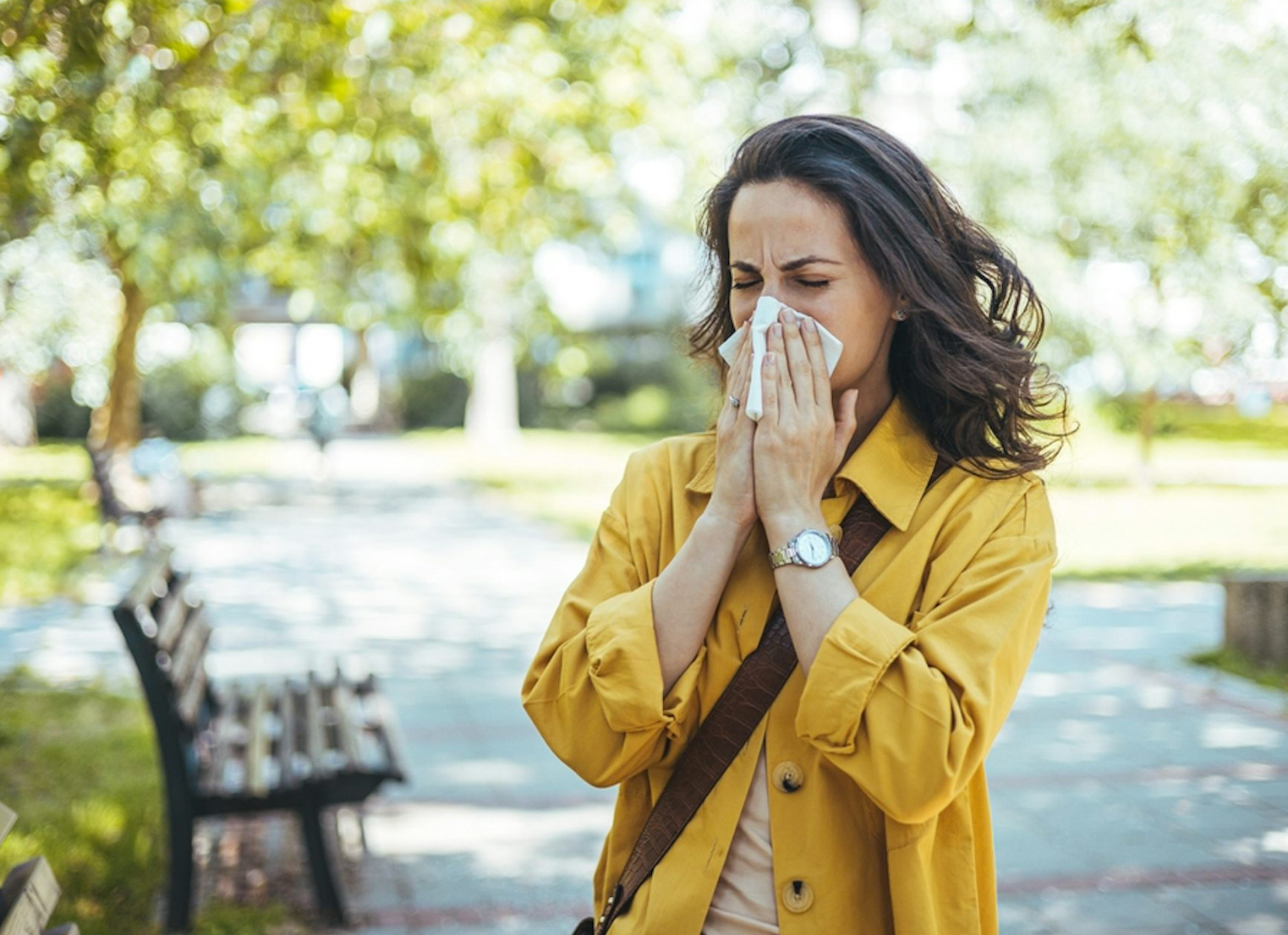 Woman sneezing into a tissue