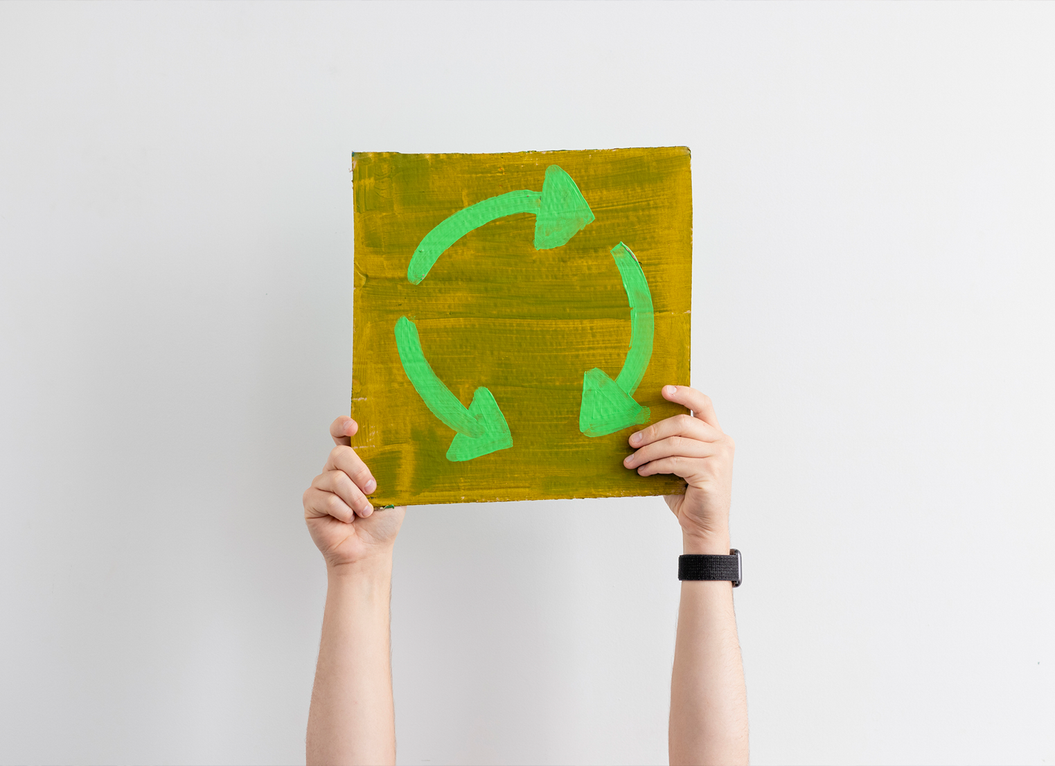 Arms holding up a circular recycling sign