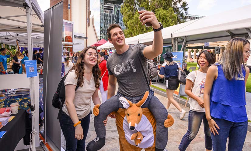 Two students take a selfie, one student is wearing a kangaroo suit.
