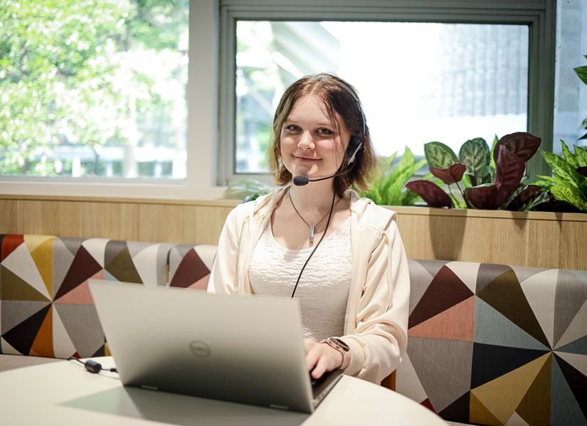 Young woman working on her laptop wearing a headset indicating that she's playing computer games or recording commentary on a livestream