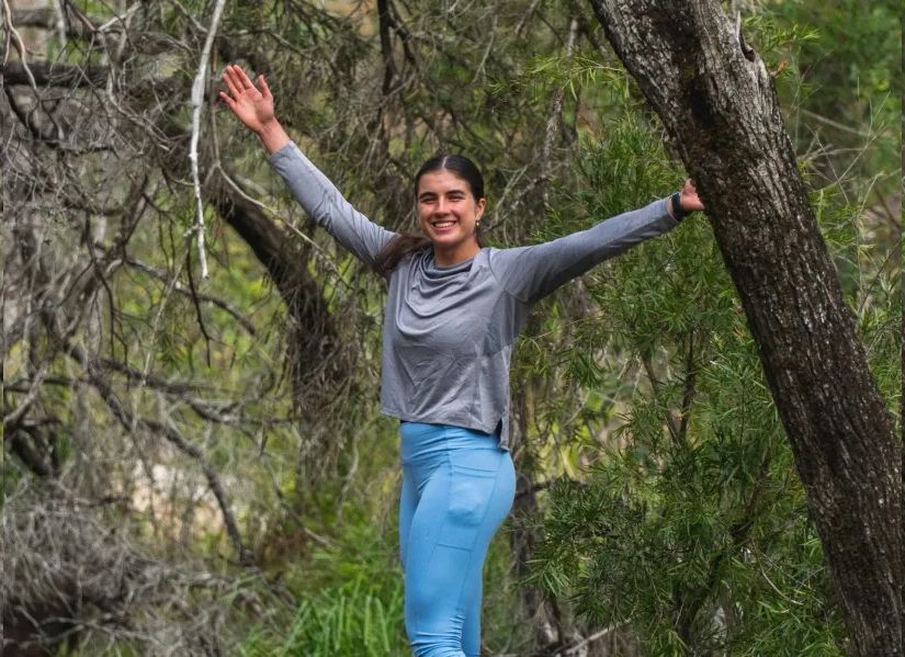 happy environmental science student reaching her arms in a wide, joyous gesture in nature