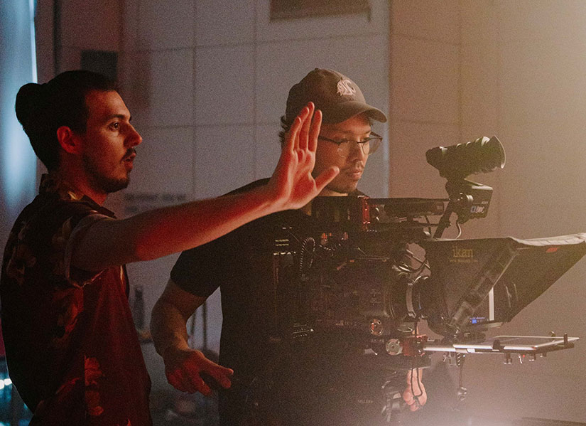 Two people behind a camera directing a shot