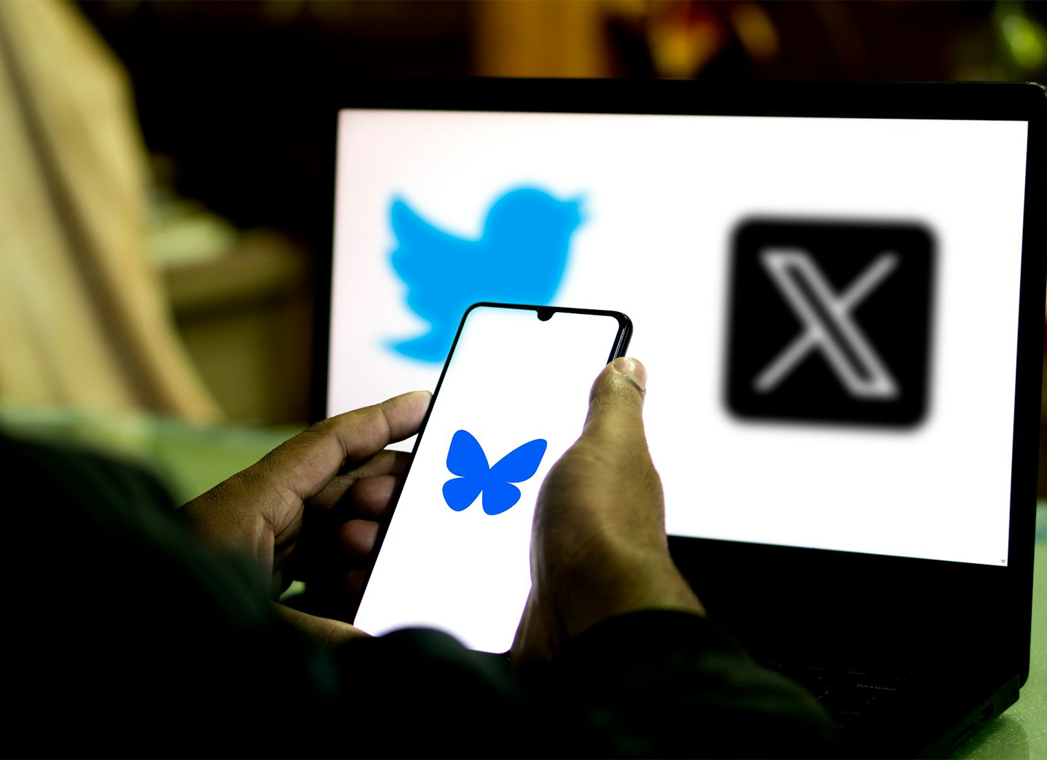 Hands holding a smart phone showing the blue butterfly Bluesky logo.