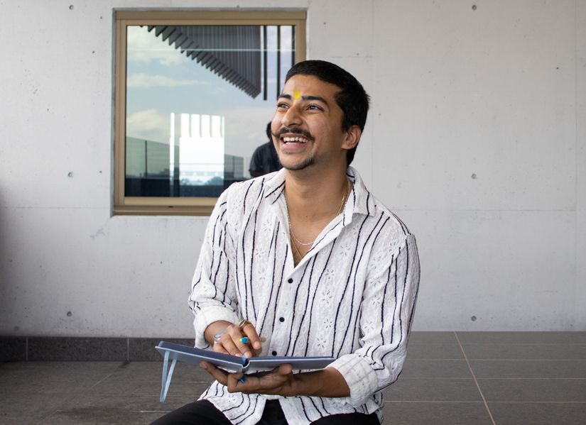 Young Indian man sits with a notebook, reflecting on his study experience 