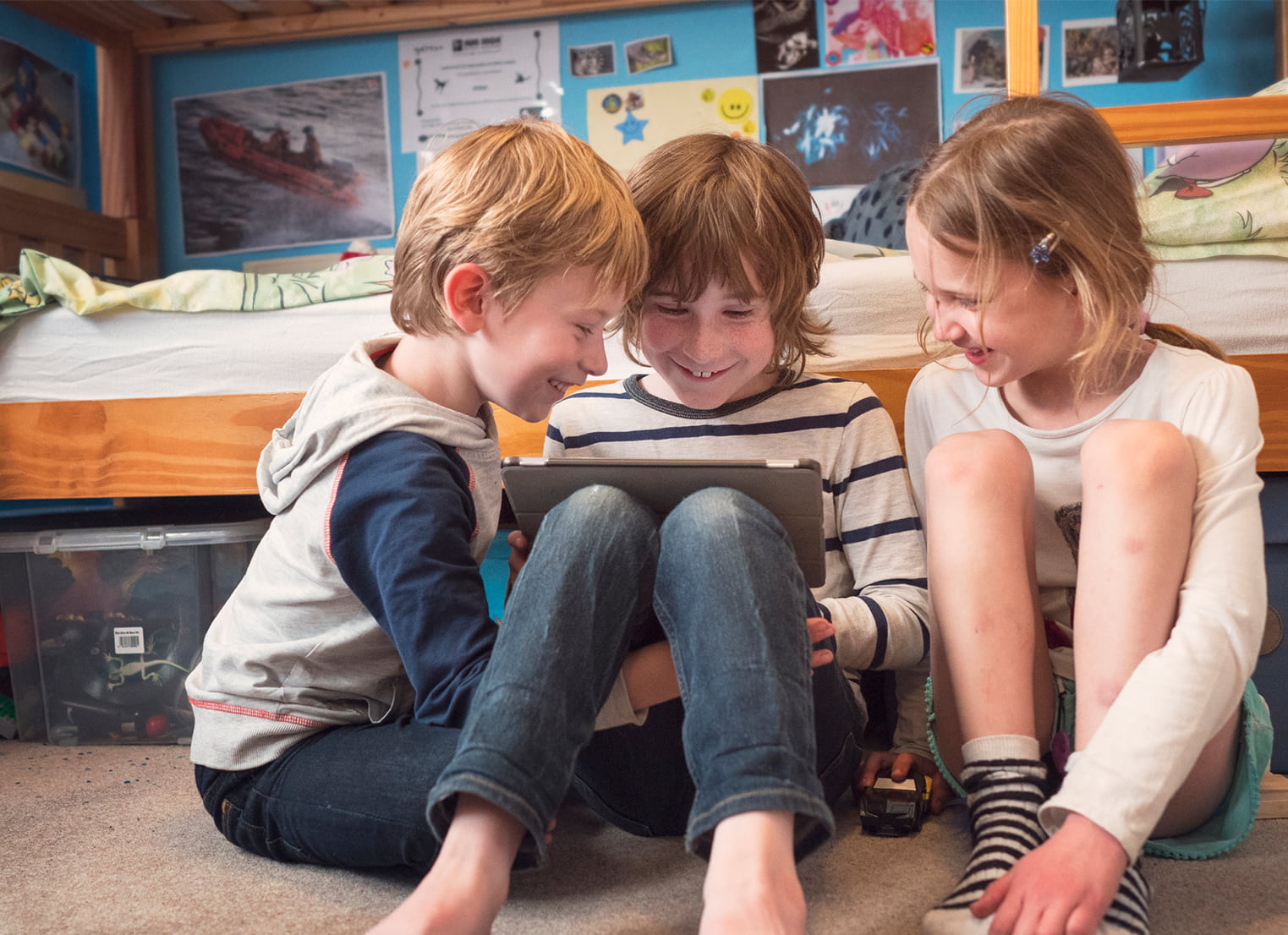 Three children sitting on floor with tablet