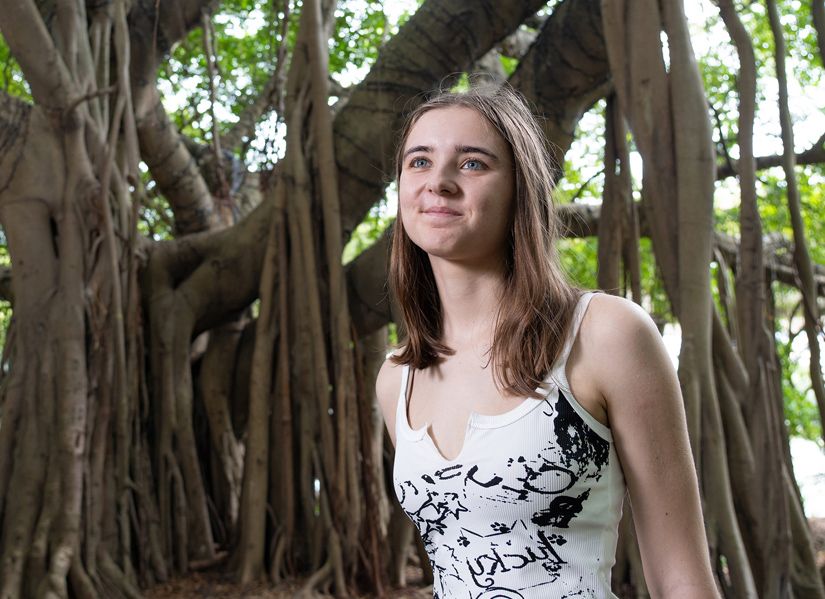 Young women standing among mangroves, gazing up with a hopeful expression